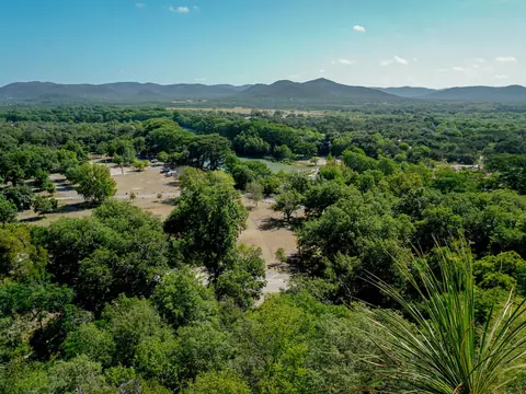 Wooded Texas hills under a blue sky, seen from above