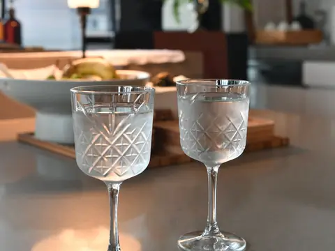 Two crystal glasses of water on a kitchen counter