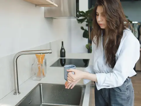 A kitchen sink with a brushed steel faucet