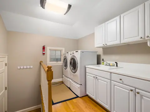 A laundry room with a washer, a dryer and white cabinets