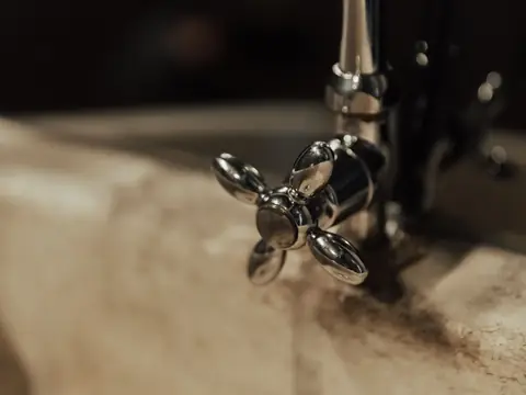 A cross-handle metal faucet on a marble sink