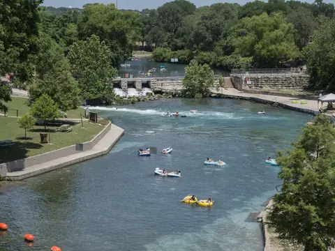 The Comal River curving through Prince Solms Park in New Braunfels, Texas, with tubers on the water