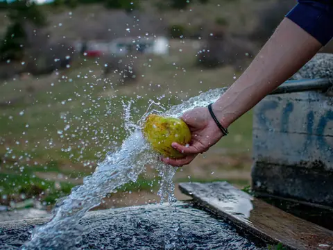Water splashing as a piece of fruit is rinsed outdoors
