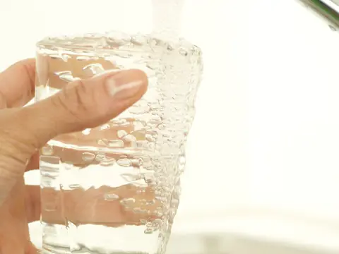 A glass being filled with water at a chrome tap