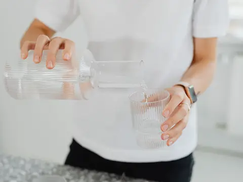 Water poured from a glass carafe into a glass