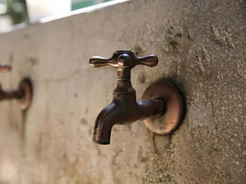 Two old metal taps on a weathered concrete wall