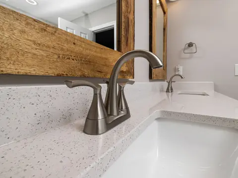 A brushed nickel faucet on a white quartz bathroom vanity
