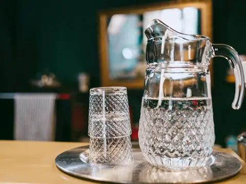 A glass pitcher and a glass of water on a tray
