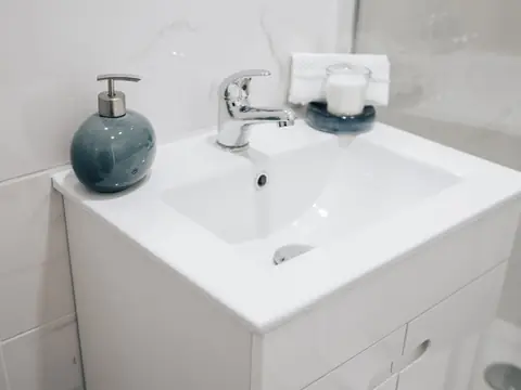 A white bathroom vanity with a chrome faucet