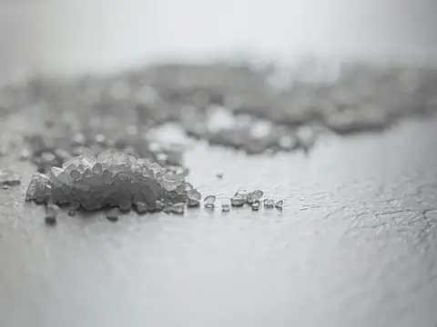 Coarse salt crystals scattered on a gray surface