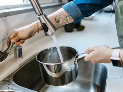 Filling a steel pot with tap water at a kitchen sink
