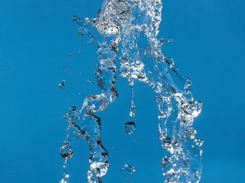 A stream of clear water splashing against a blue sky