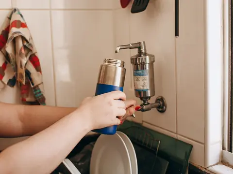 A water bottle filled at a tap with a filter fitted to it
