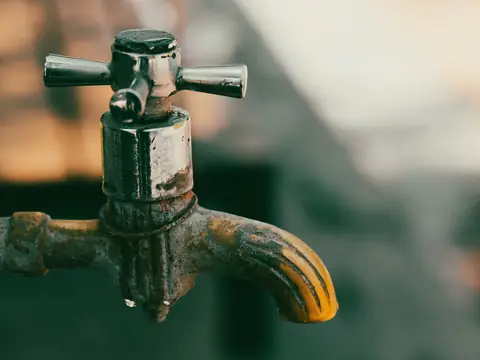 An old metal tap with a drop of water at its spout